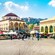 A group of people walking in a town square with buildings and a dome in Monastiraki in Athens, Greece